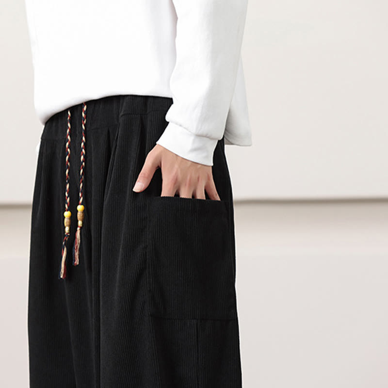 Black fine-wale corduroy harem pants featuring deep side patch pockets and a beaded drawstring waist.