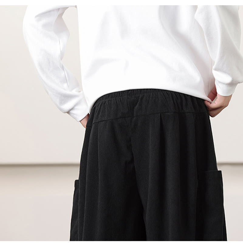 Black fine-wale corduroy harem pants featuring a loose silhouette, elastic waist, and deep side patch pockets.