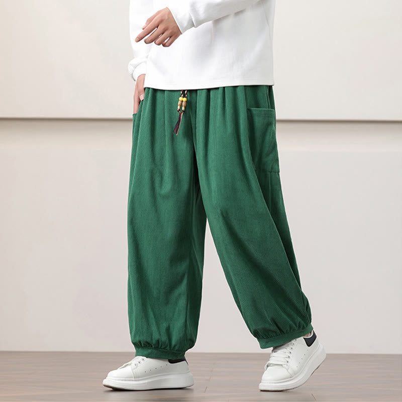 Green fine-wale corduroy harem pants with side patch pockets, beaded drawstring waist, and cuffed ankles worn with sneakers.