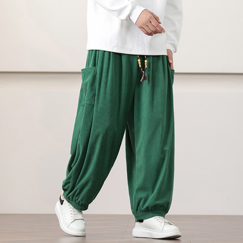 Dark green fine-wale corduroy harem pants featuring side patch pockets, a beaded drawstring waist, and cuffed ankles.