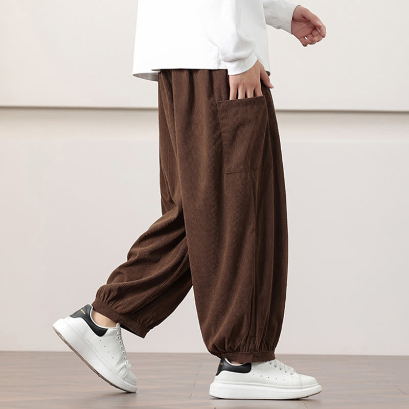 Brown fine-wale corduroy harem pants with side patch pockets and cuffed ankles, styled with white sneakers.