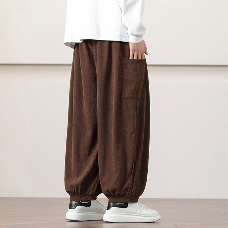 Brown fine-wale corduroy harem pants with side patch pockets and gathered cuffed ankles worn with white sneakers.