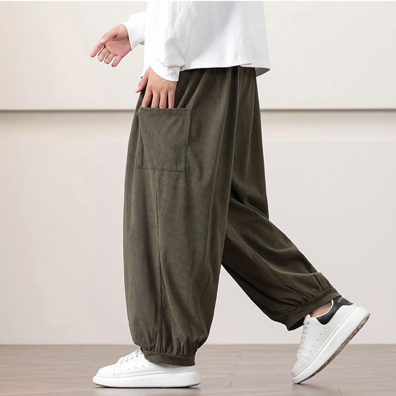 Olive green fine-wale corduroy harem pants with side patch pockets, elastic waist, and cuffed ankles worn with sneakers.