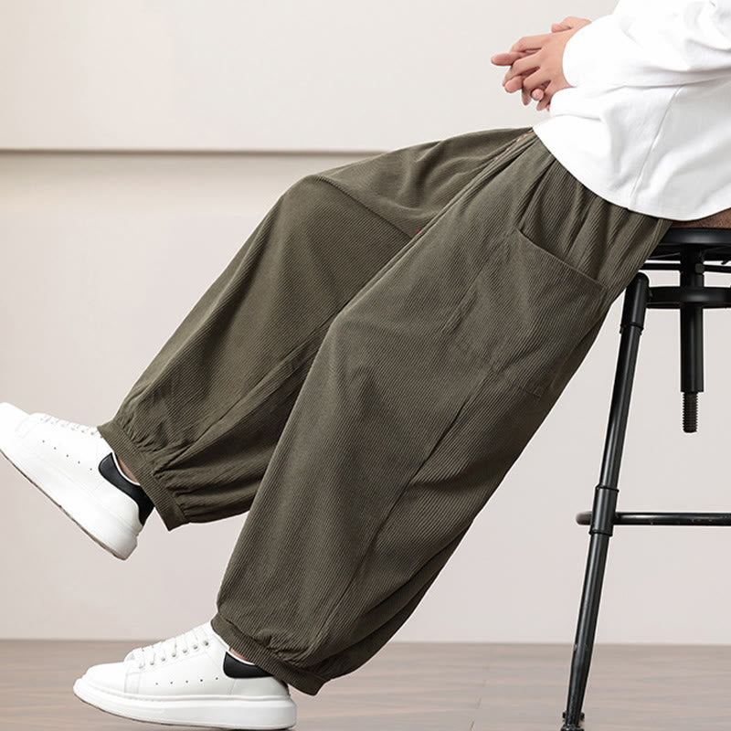 Olive green fine-wale corduroy harem pants with side patch pockets, elastic cuffed ankles, and a relaxed, loose-leg fit.