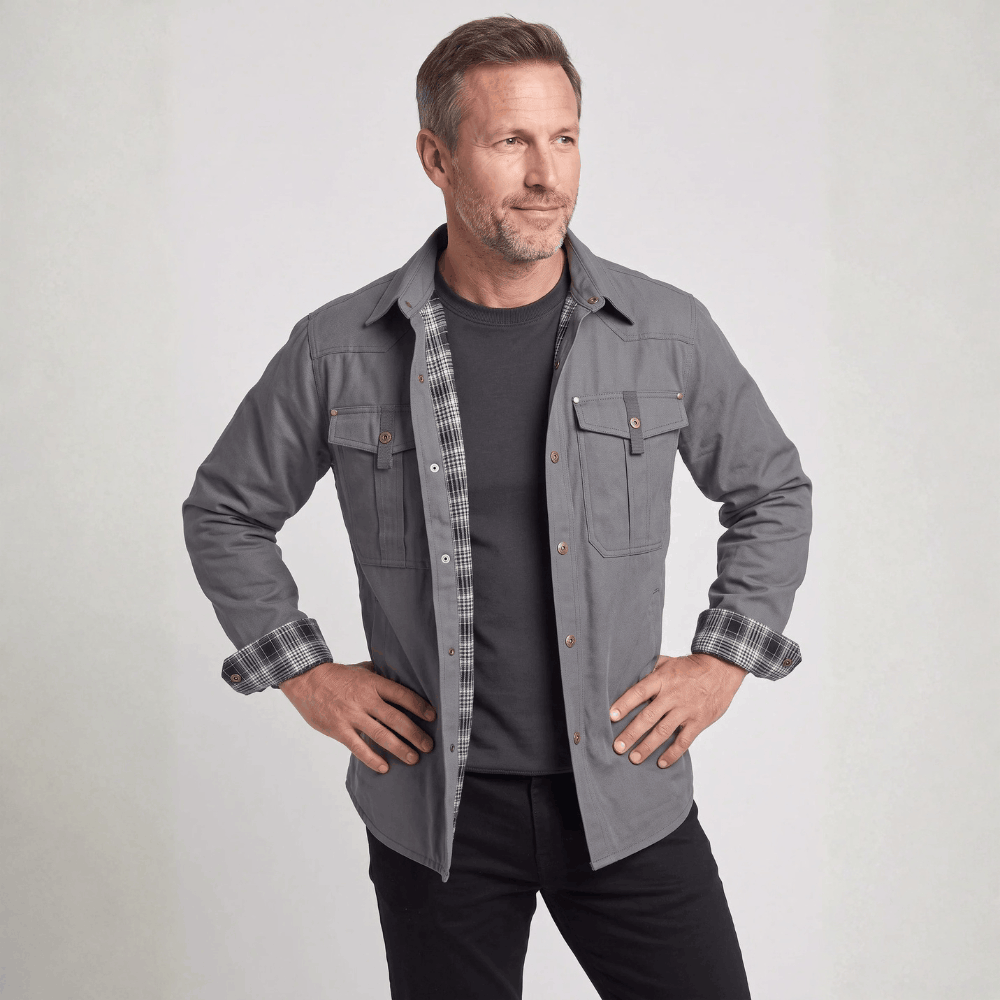 Front view of a model posing with hands on hips wearing a charcoal gray flannel-lined barn jacket with rolled cuffs.