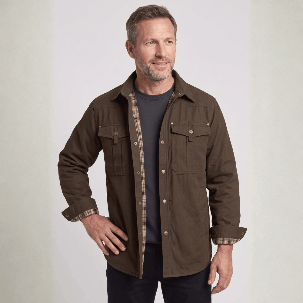 Front view of a model wearing a dark brown canvas barn jacket with flannel-lined cuffs and metal snap closures.