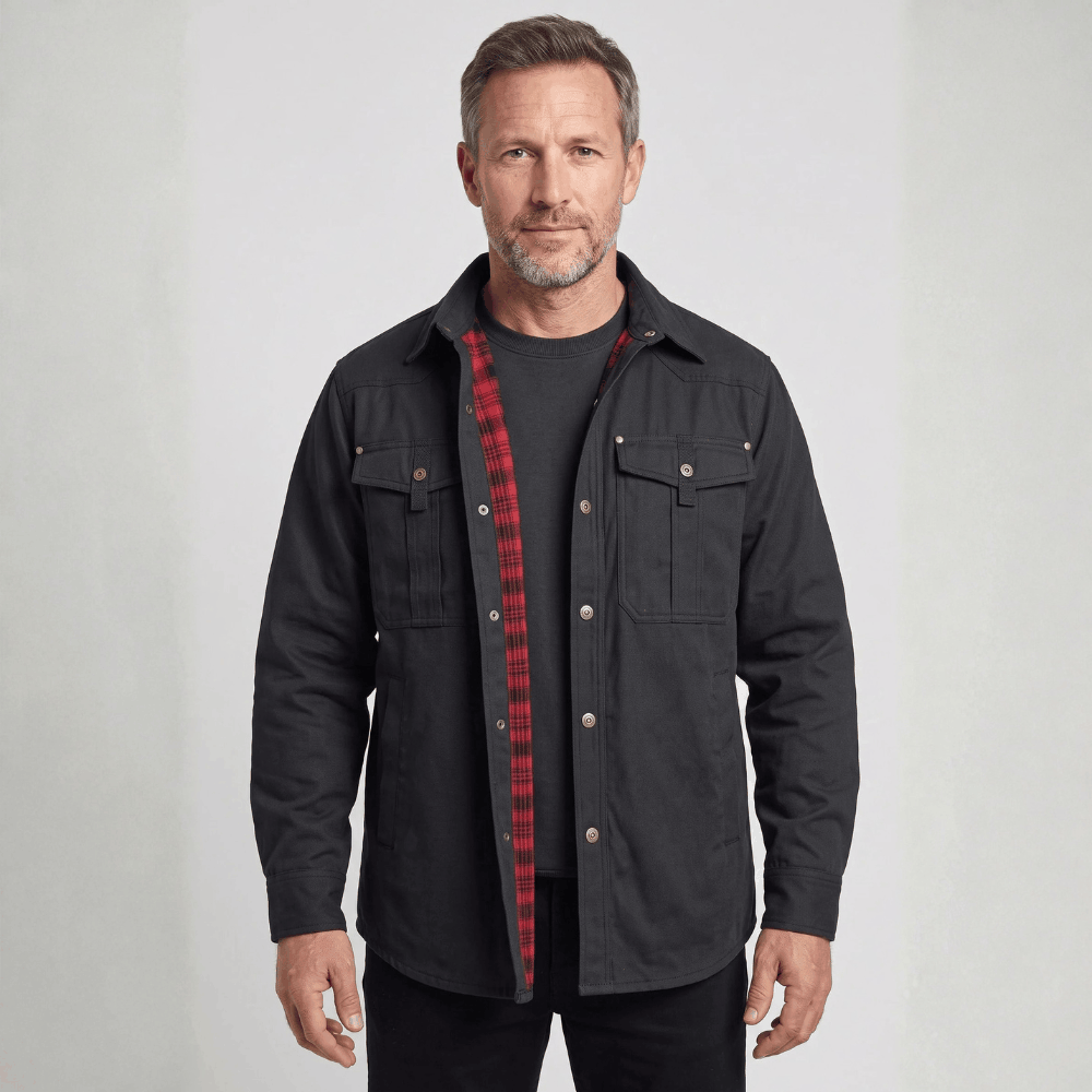 Front view of a model wearing an open black flannel-lined barn jacket with metal snaps, dual chest flap pockets, a spread collar, and red plaid flannel lining visible along the placket.