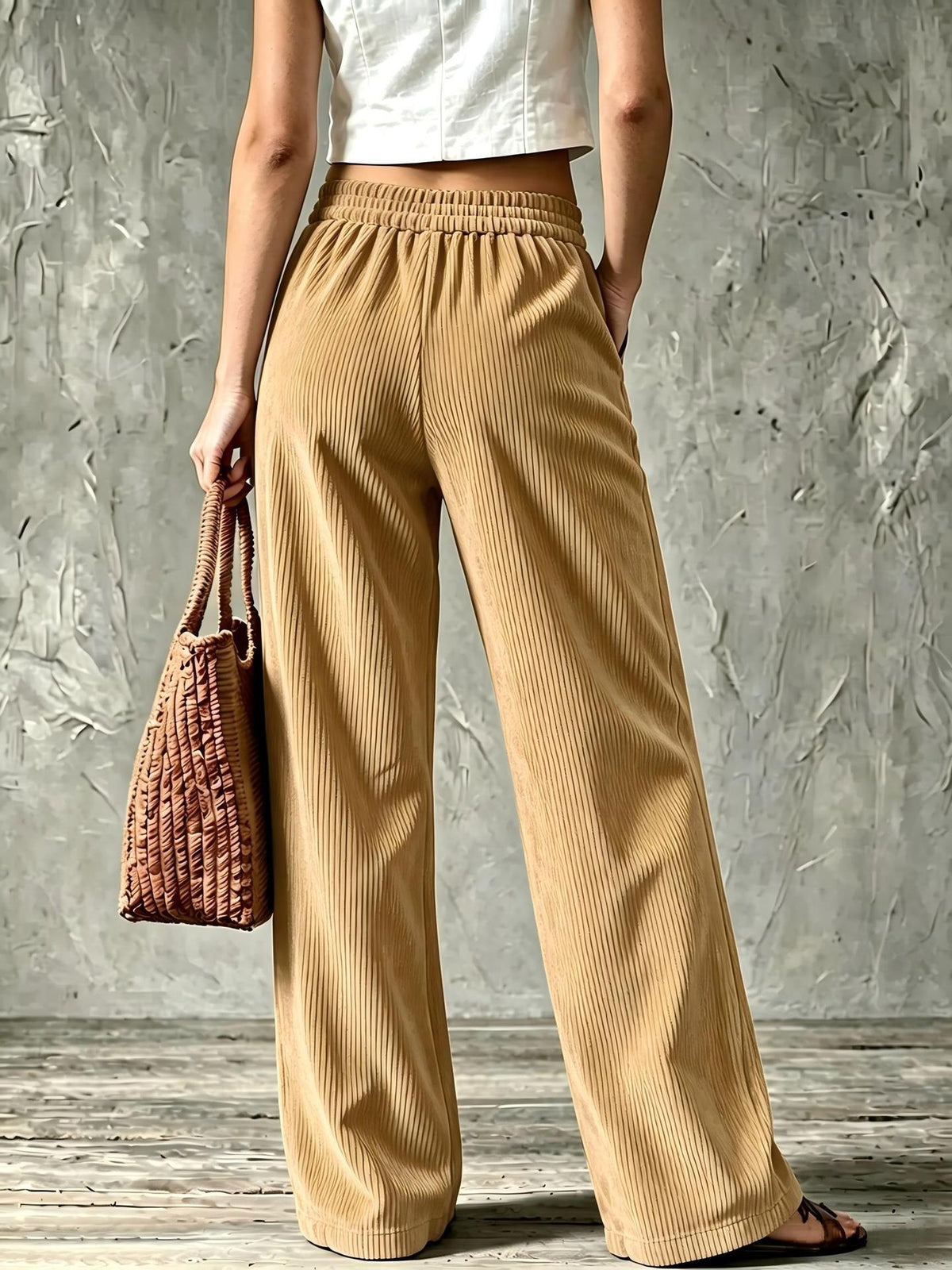 Khaki fine-wale corduroy wide-leg pants with a relaxed fit and elasticized waistband, paired with a woven handbag.