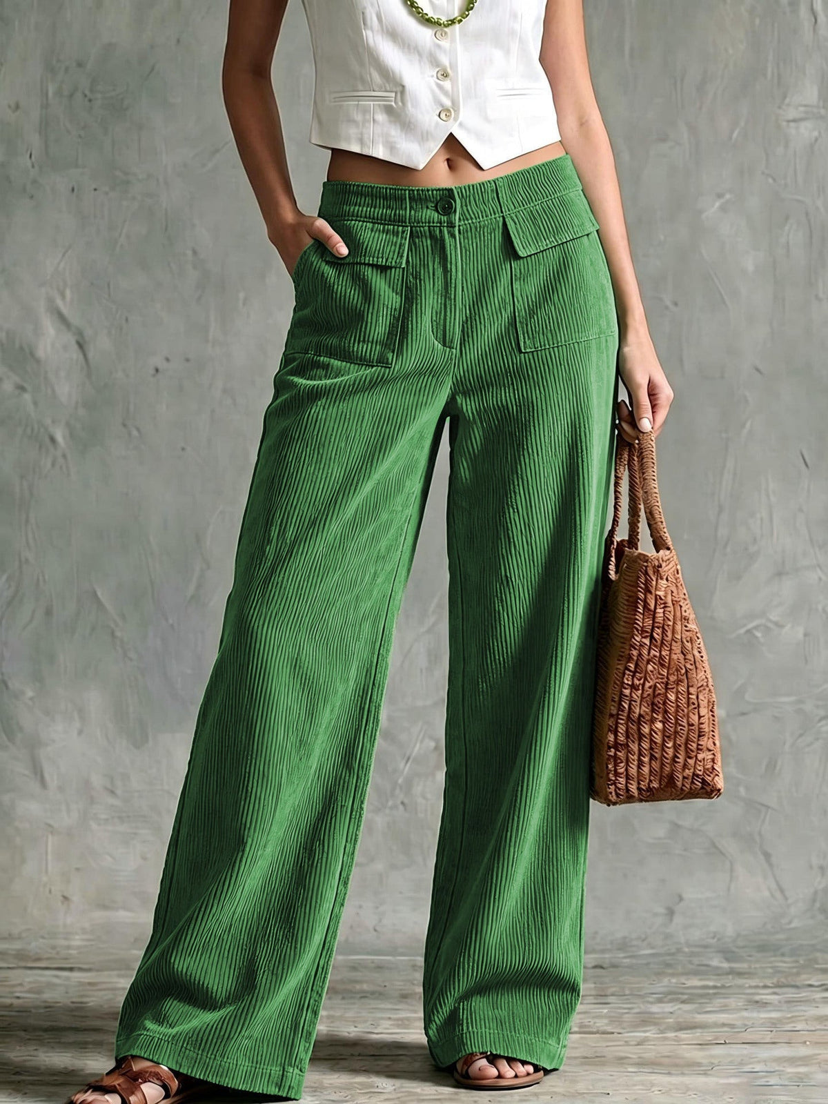 Green fine-wale corduroy wide-leg pants with utility flap pockets and a button-zip fly, styled with a cropped white vest.