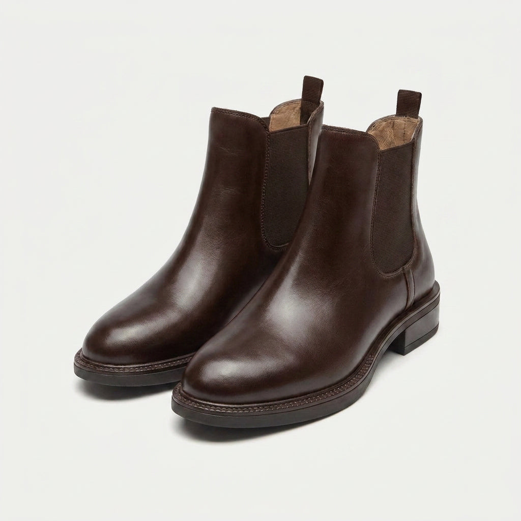 Dark brown vegan leather Chelsea boots with elastic side panels, a smooth polished finish, and a low stacked heel.