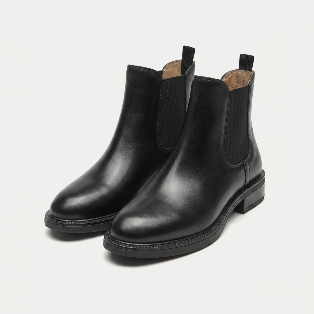 Black vegan leather Chelsea boots with polished uppers, elastic side panels, rear pull tabs, and low stacked heels.