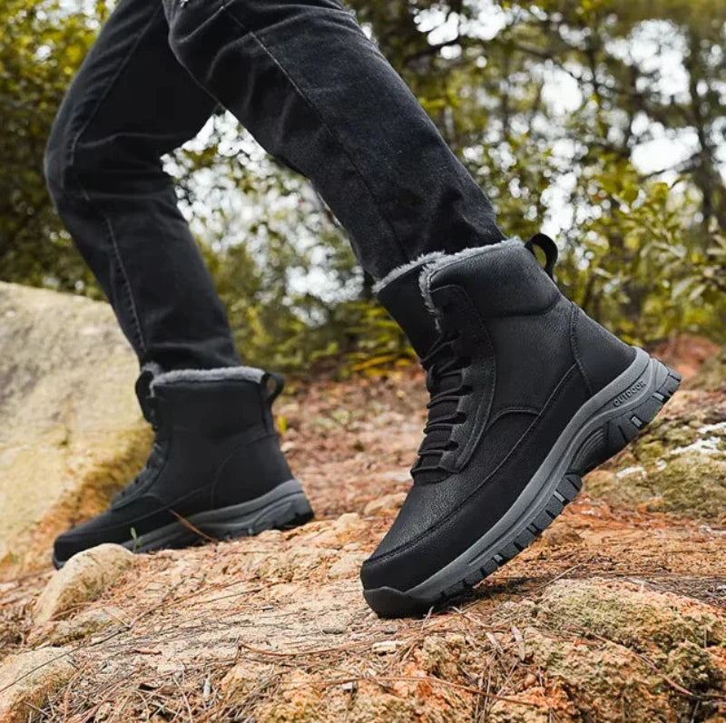 Man wearing black fleece-lined lace-up ankle boots outdoors on rocky ground