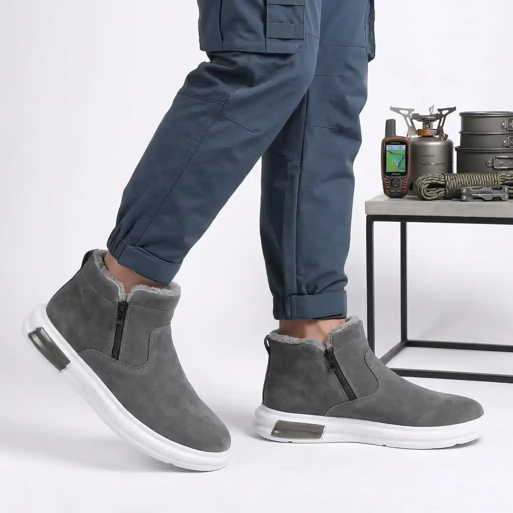 Man in blue trousers wearing gray fleece-lined winter ankle boots with side zip