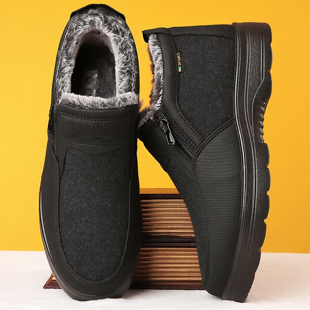 Black winter boots with plush fur lining, side zippers, and textured traction soles against a yellow background.