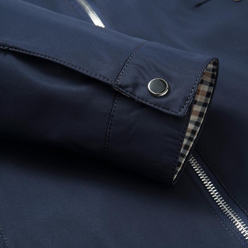 Close-up of the navy jacket sleeve cuff highlighting the snap-button tab, zipper, and premium fabric finish.