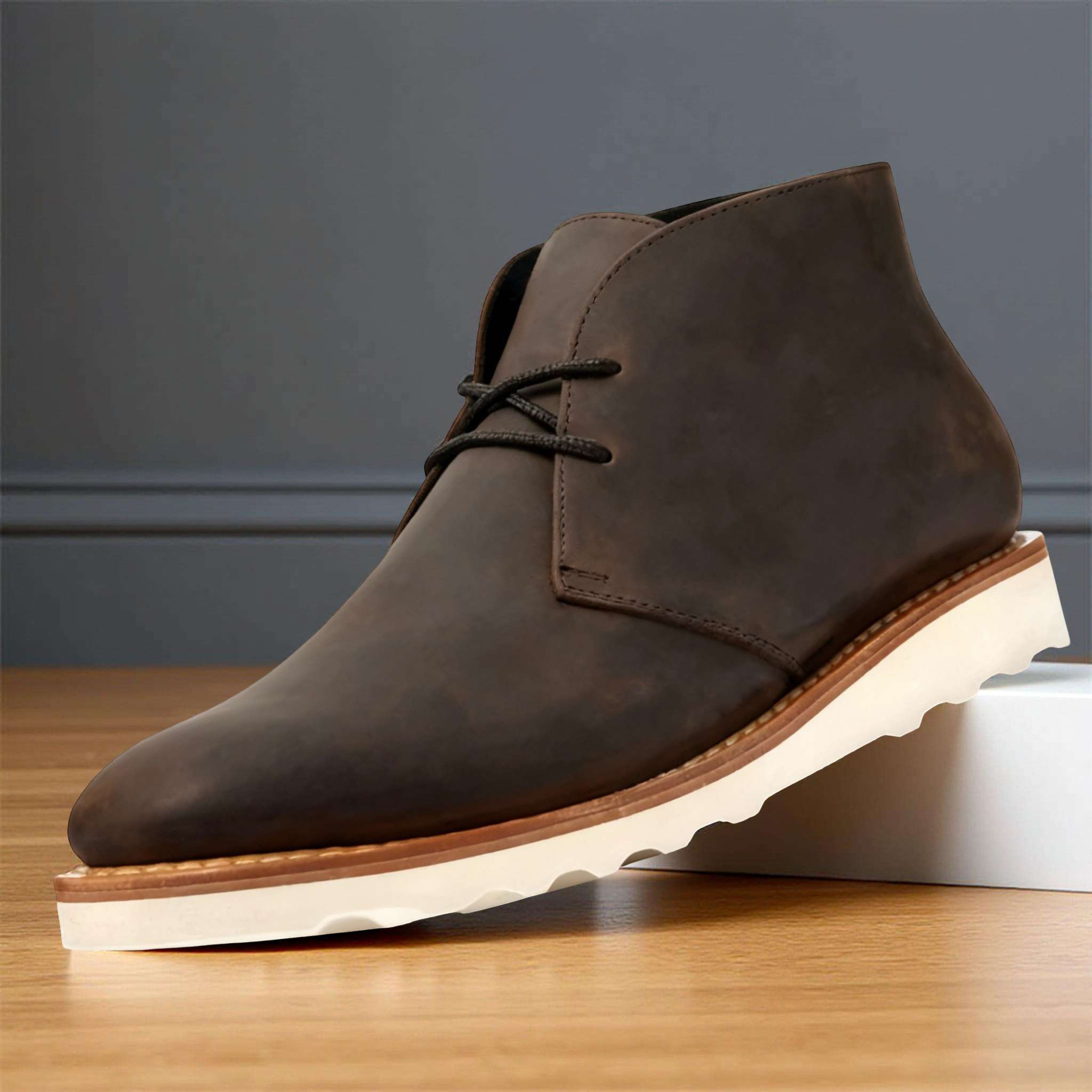 Dark brown napped leather chukka boot with a two-eyelet lace-up front, rounded toe, and thick white treaded outsole.