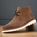 Brown napped suede chukka boots featuring a two-eyelet lace-up front, rounded toe, and a thick, white treaded rubber sole.