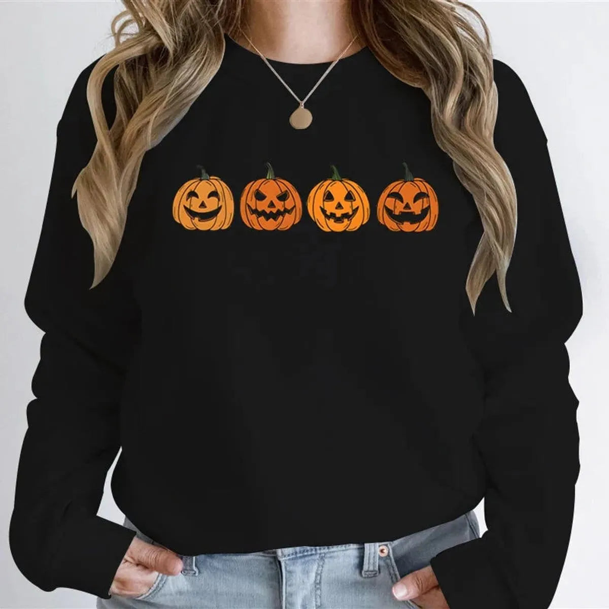 Front view of a model wearing the four-pumpkin jack-o'-lantern graphic crewneck sweatshirt in classic black.