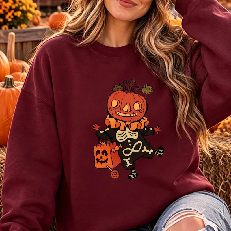 Model wearing the Halloween cartoon pumpkin skeleton graphic crewneck sweatshirt in deep maroon burgundy, posed in an outdoor festive setting.