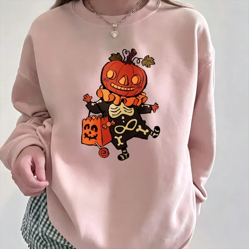 Close-up front view of a model wearing a light soft pink relaxed crewneck sweatshirt featuring a vintage cartoon graphic of a dancing skeleton with a jack-o'-lantern pumpkin head holding a trick-or-treat bag.