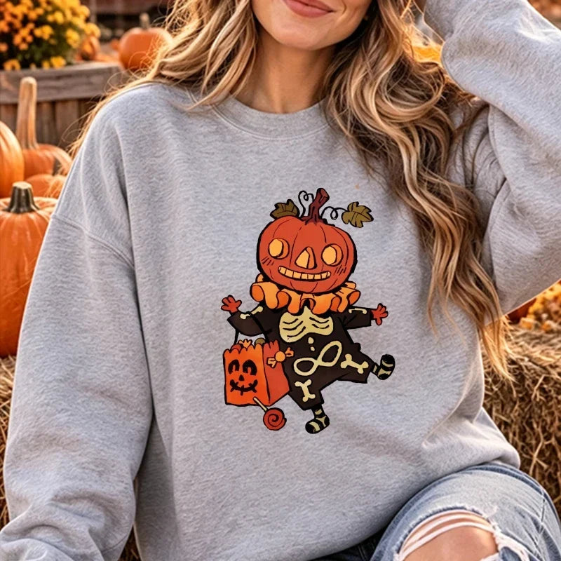 Model wearing the Halloween cartoon pumpkin skeleton graphic crewneck sweatshirt in heather gray, posed outdoors against a pumpkin patch backdrop.