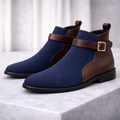 Navy blue ribbed knit ankle boots with brown leather heel panels and an adjustable gold buckle strap.