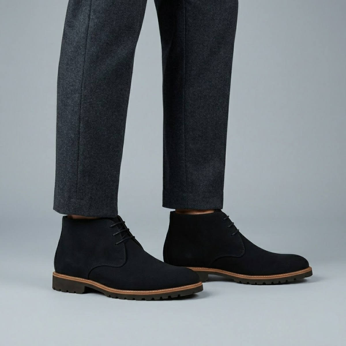 Black suede chukka boots with three-eyelet lacing, plain toe, and a durable lug tread outsole with a visible stitched welt.