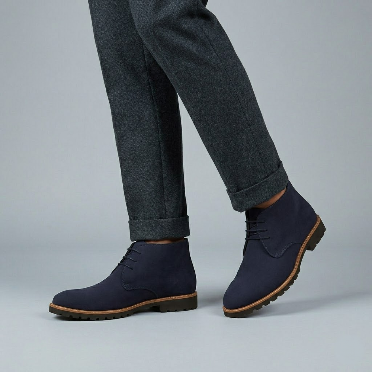 Navy suede chukka boots with a three-eyelet lace-up design, plain toe, and a sturdy brown lug tread outsole.
