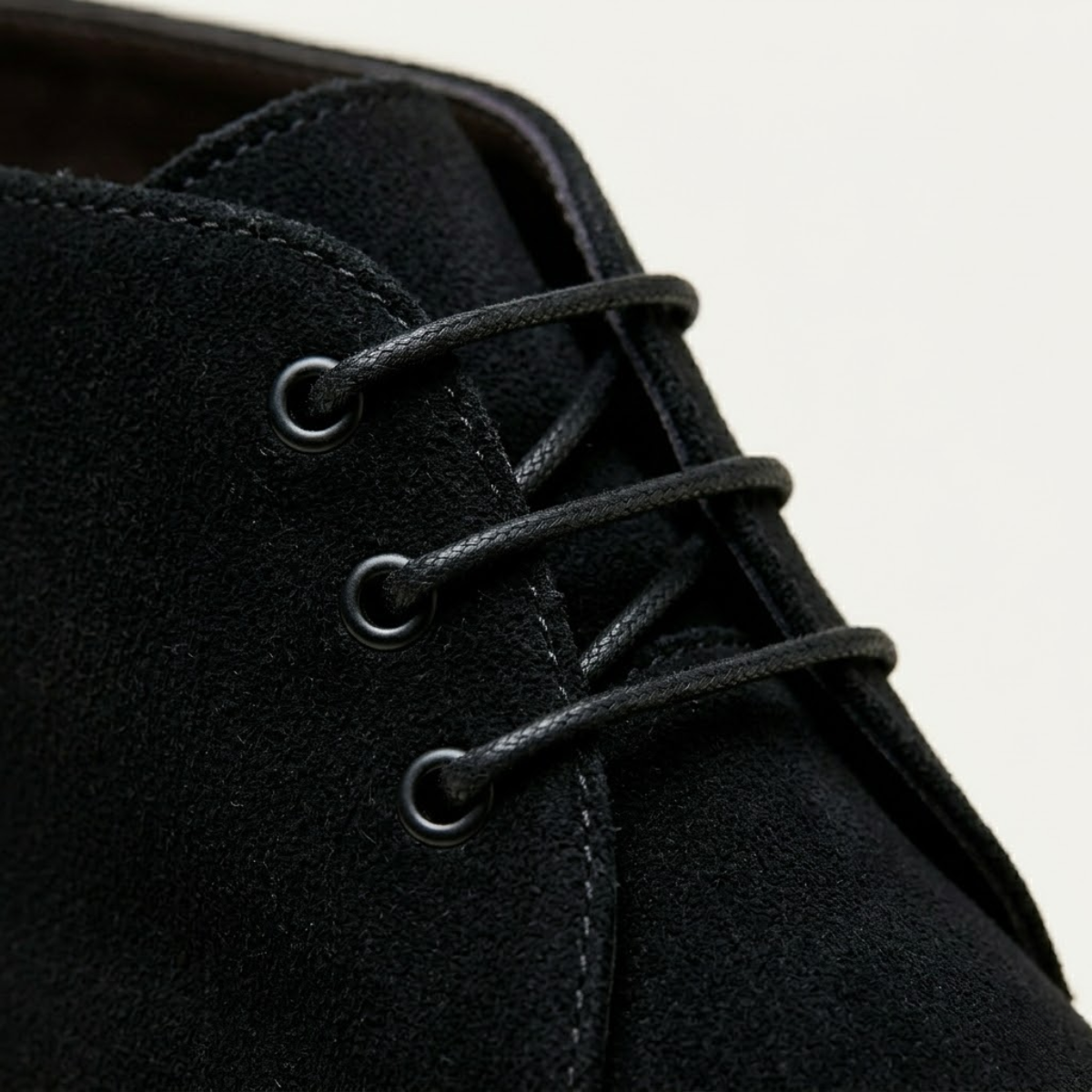Black suede chukka boot featuring a three-eyelet lace-up design with a plain toe and textured napped finish.