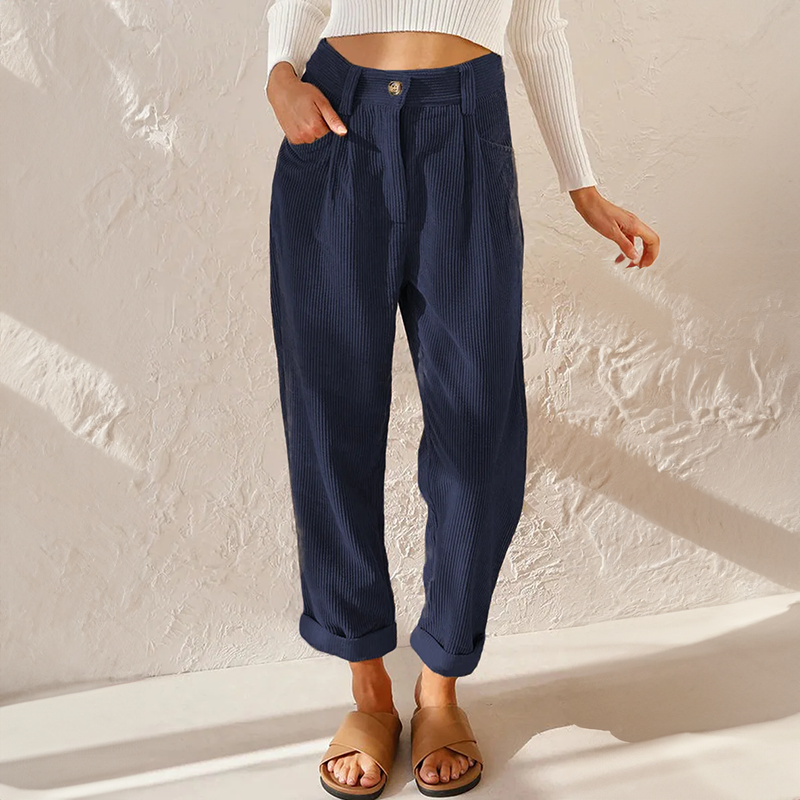 Navy blue high-waisted corduroy pants with front pleats, a relaxed tapered leg, and adjustable turn-up cuffs.