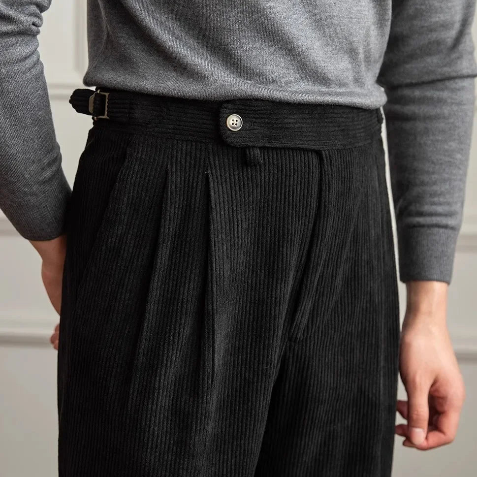 Close-up of black pleated corduroy pants showing the waistband and side adjuster