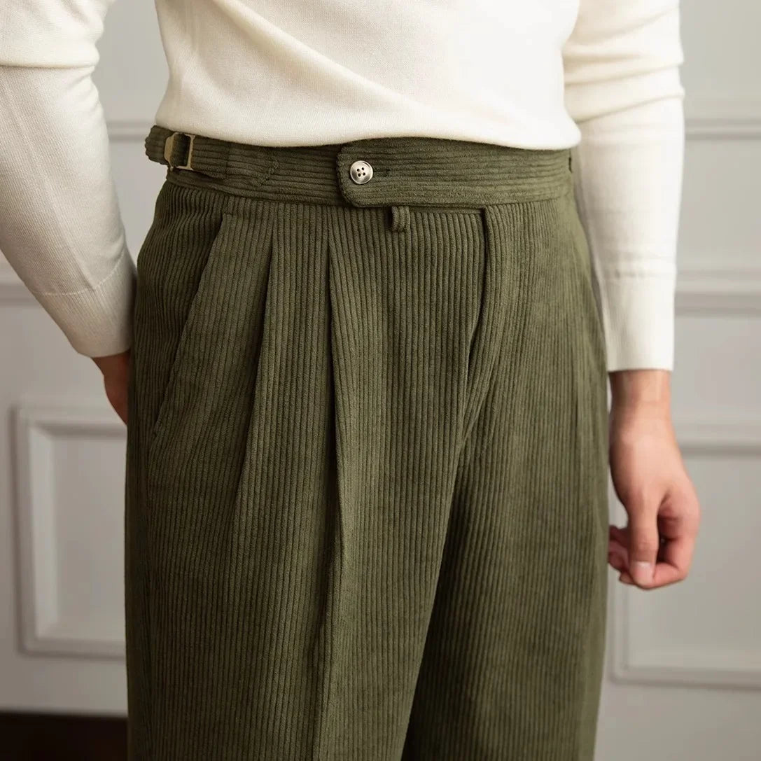 Close-up of olive green pleated corduroy pants showing the high waist and side adjusters
