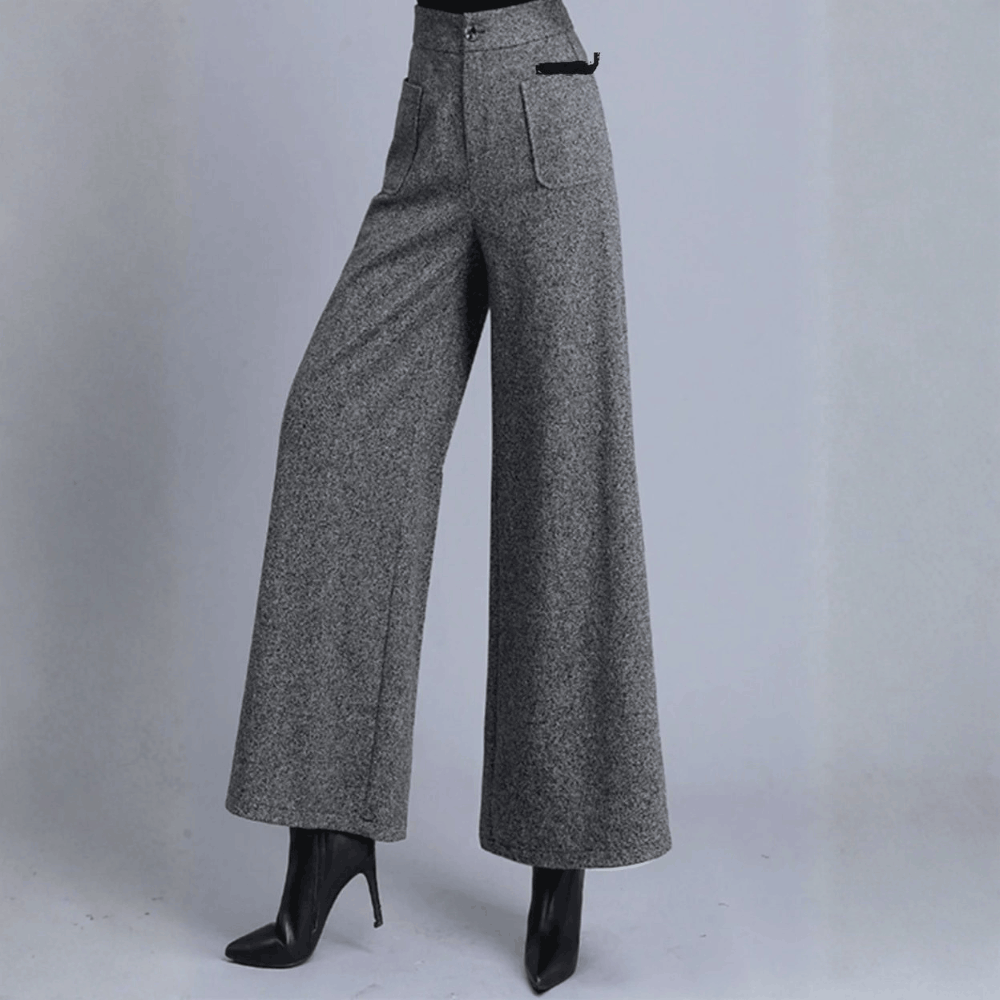Three-quarter angle of a model wearing gray wool wide-leg trousers, highlighting the high-waisted waistline and structured pocket details.