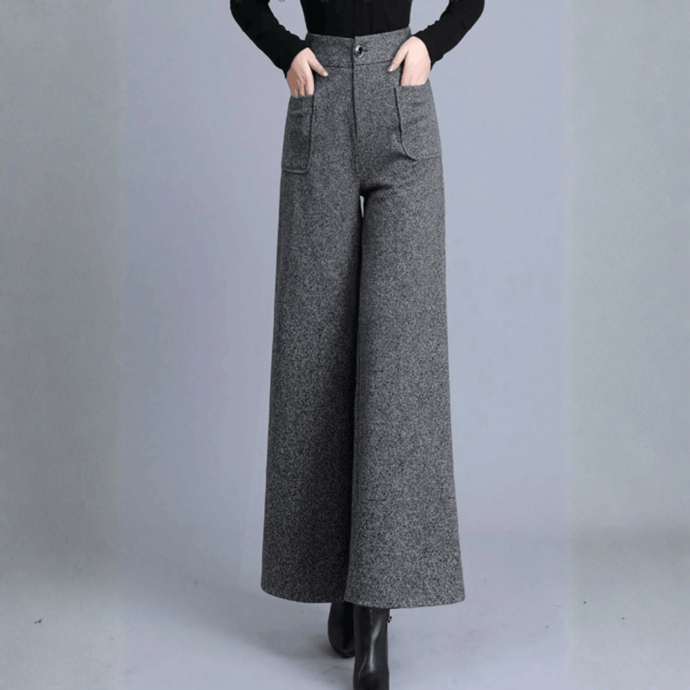 Model standing facing forward in high-waisted gray wool wide-leg pants with hands in side pockets.