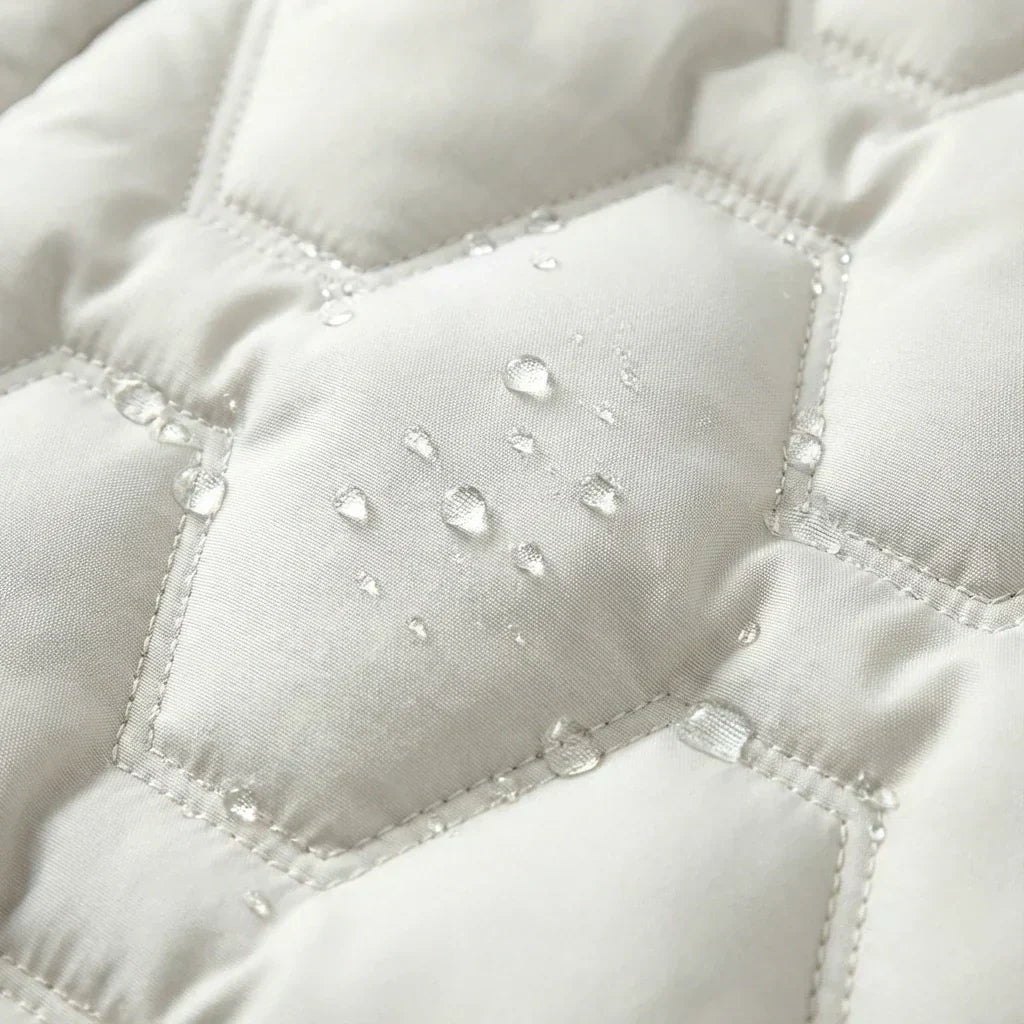 Close-up of white-colored insulated puffer fabric with water-resistant droplets and geometric quilted stitching.