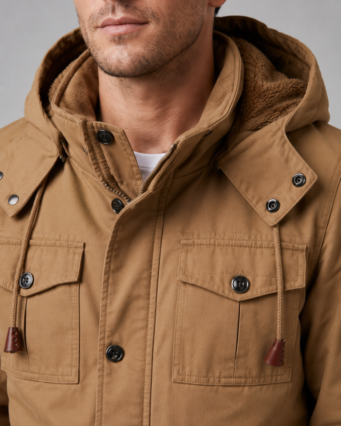 Close-up view of the upper torso and fleece-lined hood on the tan utility jacket showing the button storm placket collar.