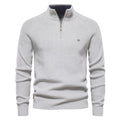 Light gray quarter-zip knit sweater featuring a stand collar, ribbed cuffs, and embroidered chest logo on a white background.