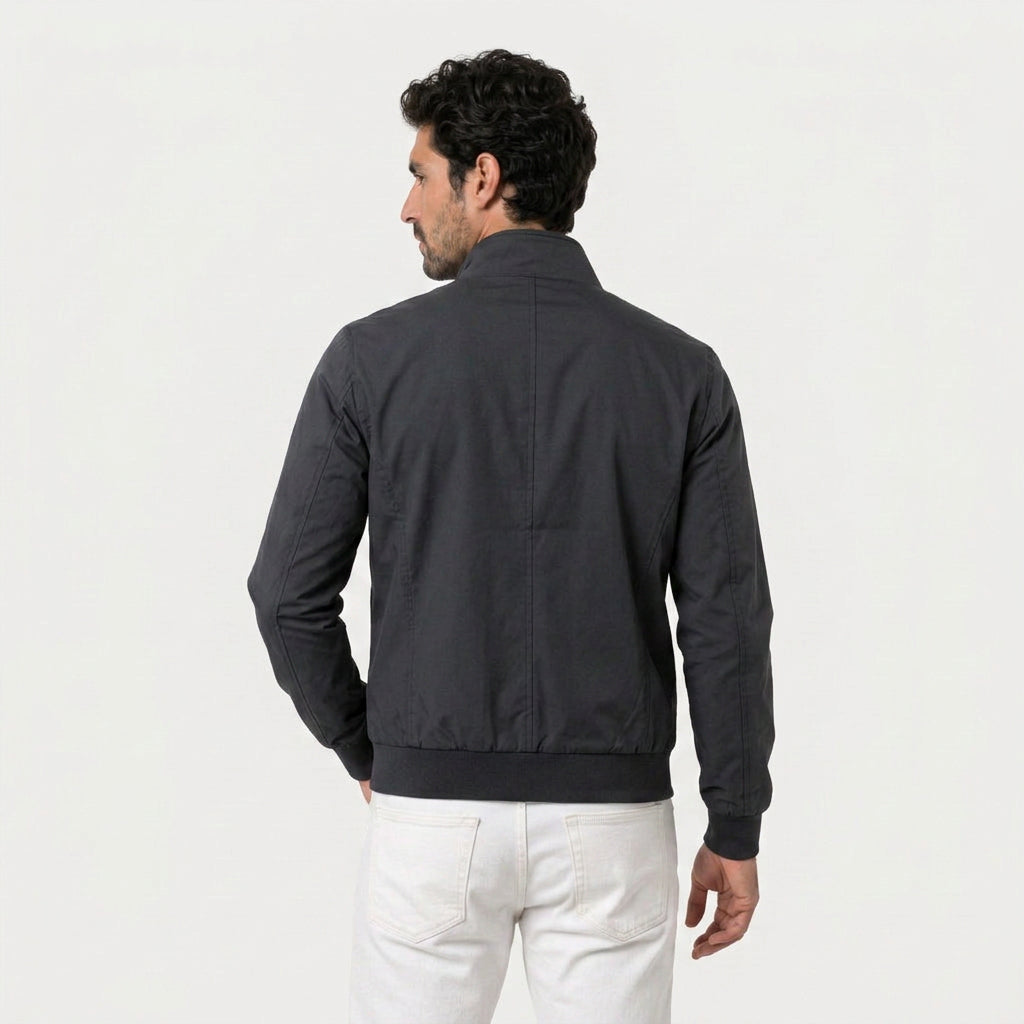 Back view of a man wearing a black bomber jacket with a stand collar and ribbed hem.