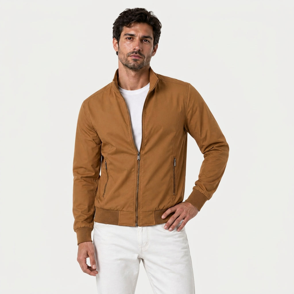 Man wearing a camel brown zip-up bomber jacket with a stand collar and plaid lining over a white T-shirt.