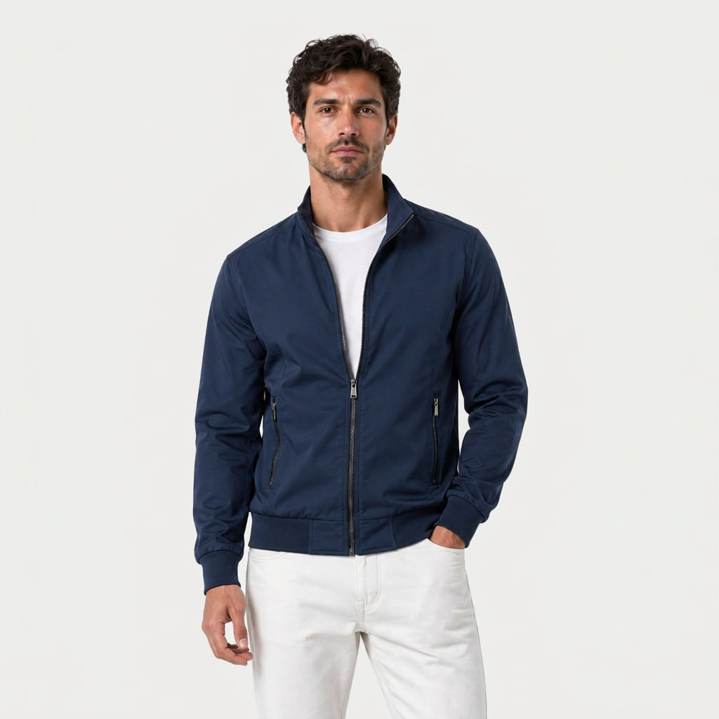 Man wearing a navy zip-up bomber jacket with a stand collar, plaid lining, and ribbed cuffs over a white T-shirt.
