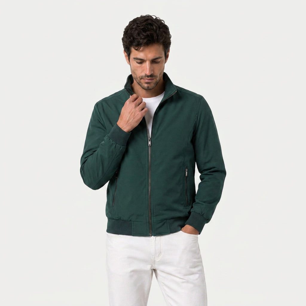 Man wearing a forest green zip-up bomber jacket with a stand collar and plaid lining.