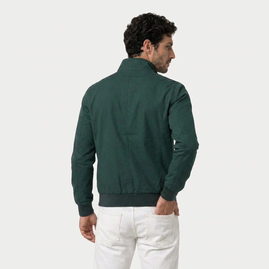 Rear view of a man wearing a forest green bomber jacket with a stand collar and ribbed hem.