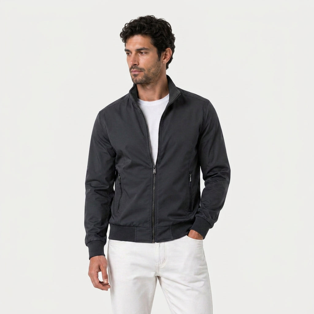 Man wearing a black zip-up bomber jacket with a stand collar over a white T-shirt.