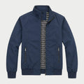 Navy zip-up bomber jacket with a stand collar, plaid lining, zippered pockets, and ribbed cuffs displayed on a white background.
