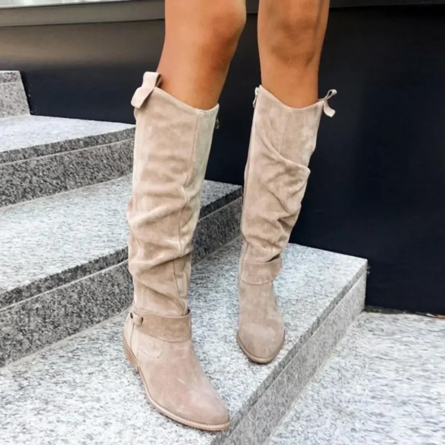 Beige slouch knee-high suede boots with pointed toes, side buckle accents, and block heels, styled with a floral dress.