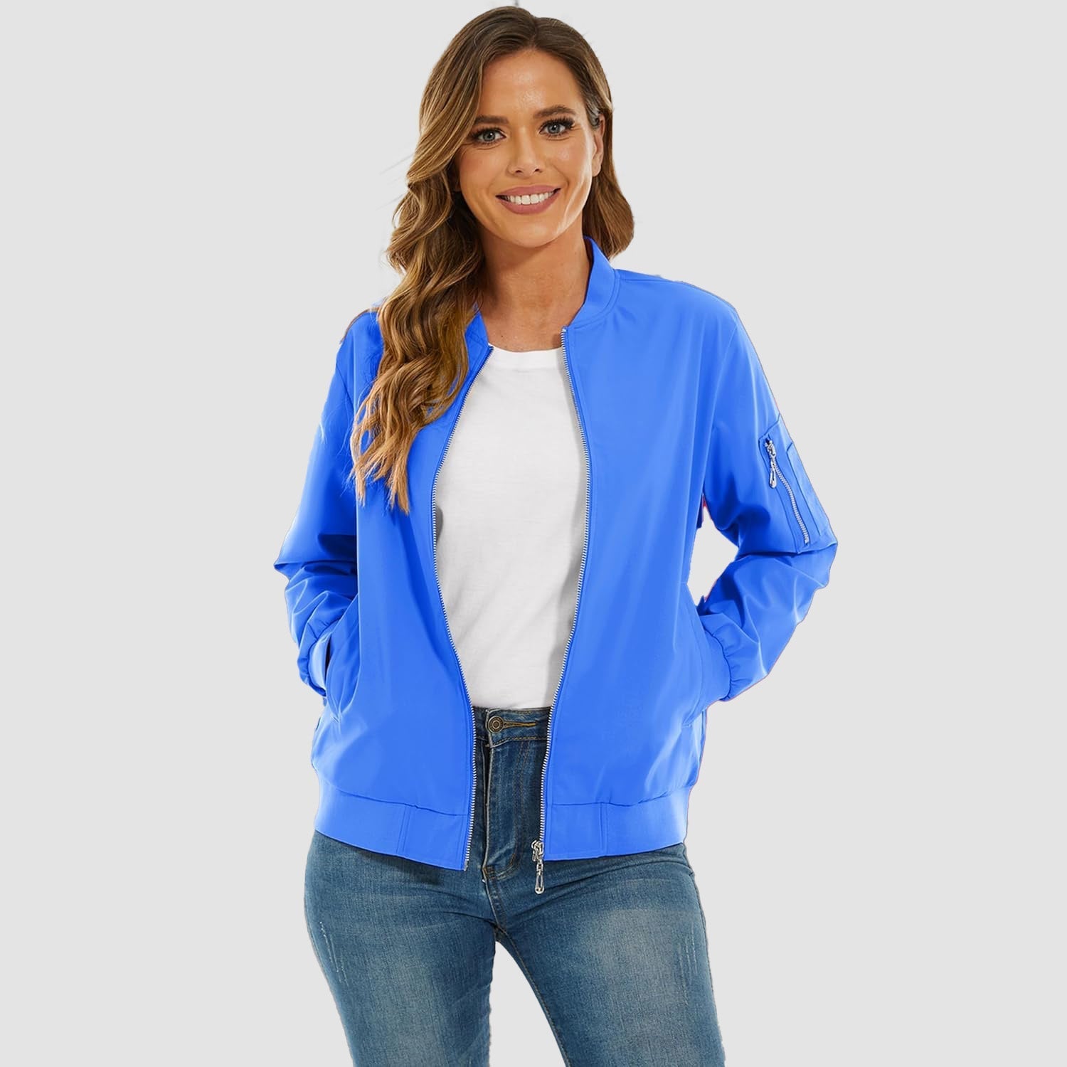 Bright blue lightweight bomber jacket with a zip-up front, ribbed trim, and utility sleeve pocket over jeans.