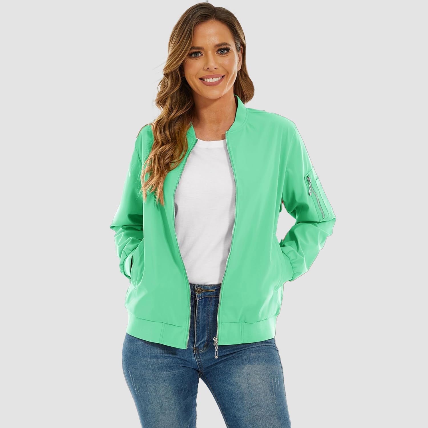Light green lightweight bomber jacket with a zip-up front, ribbed trim, and utility sleeve pocket worn over jeans.