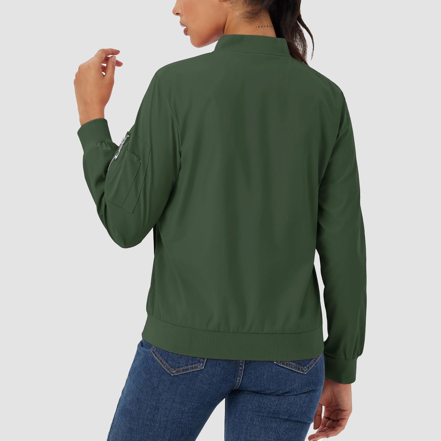 Dark green lightweight bomber jacket with a zip sleeve pocket, ribbed trim, and water-resistant finish worn with jeans.