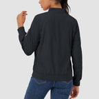 Black lightweight bomber jacket with a zip sleeve pocket, ribbed hem, and water-resistant finish worn with blue jeans.