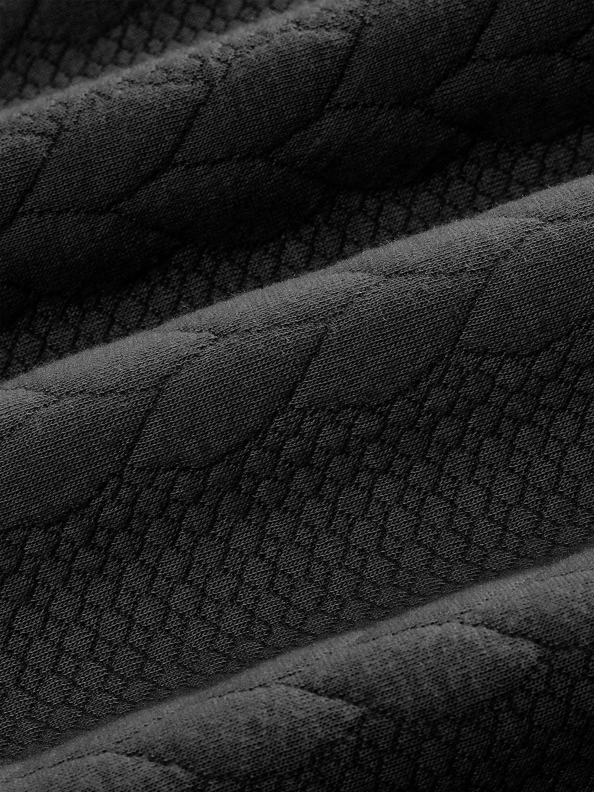 Close-up of black textured knit fabric showcasing the soft material and raised geometric knit pattern.